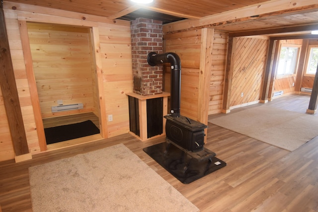 interior space featuring wood ceiling, wood walls, a wood stove, wood-type flooring, and baseboard heating