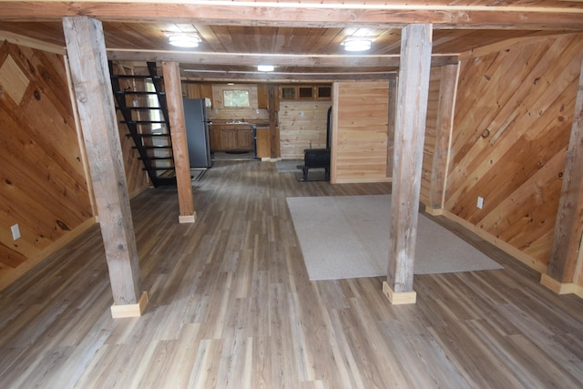 basement featuring wood ceiling, a wood stove, wooden walls, hardwood / wood-style flooring, and stainless steel refrigerator