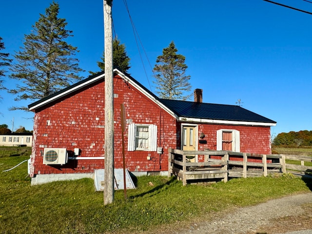 rear view of house with ac unit and a lawn