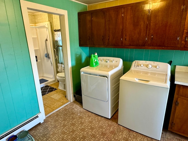 laundry area with cabinets, wood walls, washer and dryer, and a baseboard radiator