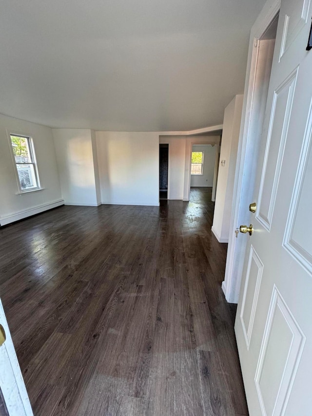 spare room featuring a baseboard heating unit and dark wood-type flooring