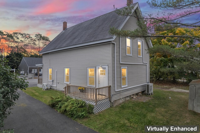 property exterior at dusk with a lawn and central air condition unit