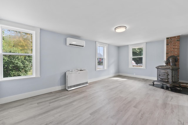 5 Harbor Rd, Friendship, ME 04547 - unfurnished living room with a wall unit AC, a wood stove, wood finished floors, baseboards, and heating unit