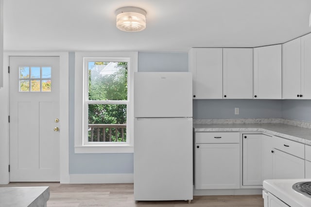 kitchen featuring white appliances, white cabinetry, and light hardwood / wood-style flooring