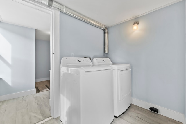 clothes washing area with light hardwood / wood-style flooring and washing machine and dryer