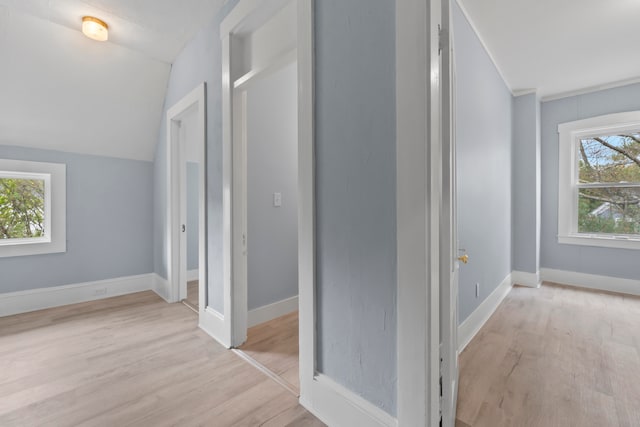 hallway with lofted ceiling, plenty of natural light, and light hardwood / wood-style floors