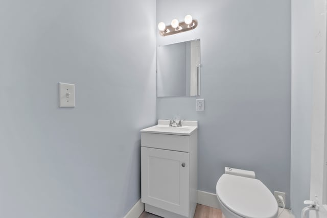 bathroom with wood-type flooring, vanity, and toilet