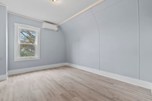 additional living space featuring light wood-type flooring and a wall mounted air conditioner