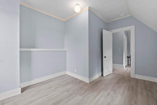 spare room with light wood-type flooring, crown molding, and lofted ceiling