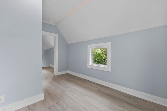 additional living space with vaulted ceiling with skylight and light hardwood / wood-style floors