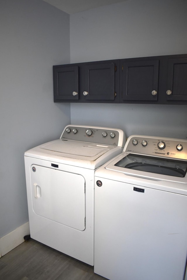 clothes washing area featuring dark wood-type flooring, washer and dryer, and cabinets