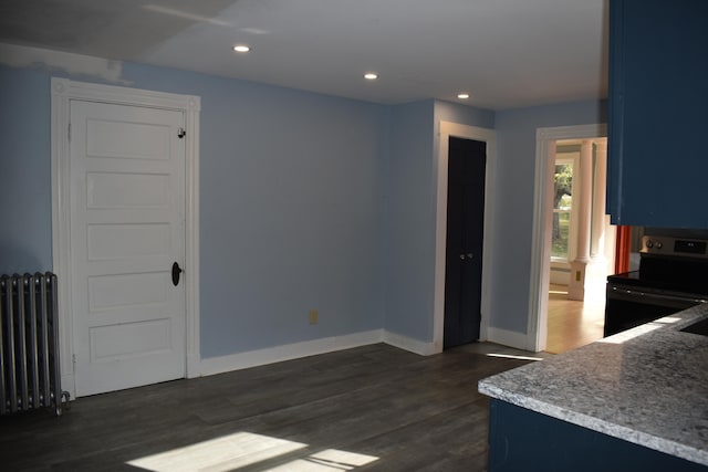 kitchen with radiator heating unit, blue cabinets, dark wood-type flooring, and black stove