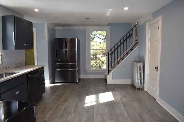 kitchen with light stone counters, radiator, stainless steel refrigerator with ice dispenser, black dishwasher, and dark hardwood / wood-style flooring