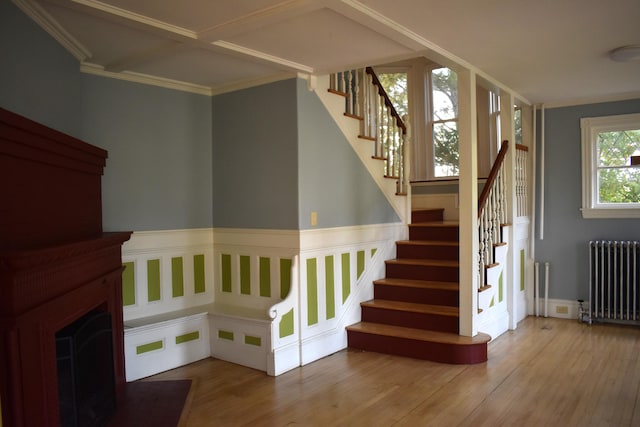 stairs featuring radiator, hardwood / wood-style flooring, and crown molding