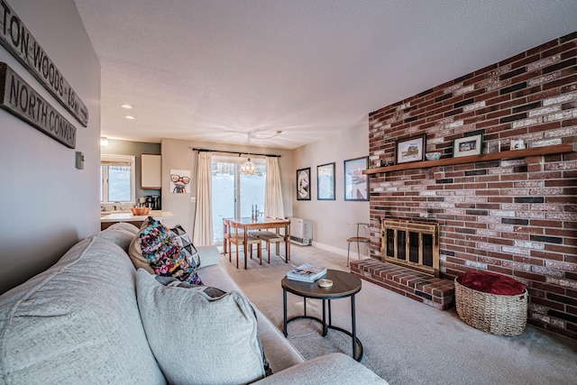 carpeted living room with a textured ceiling, a chandelier, and a brick fireplace