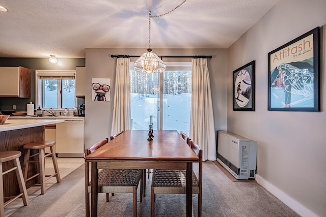 carpeted dining room featuring a textured ceiling, heating unit, and a chandelier