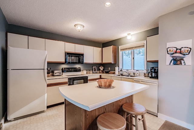 kitchen featuring sink, white appliances, a kitchen island, a textured ceiling, and a breakfast bar