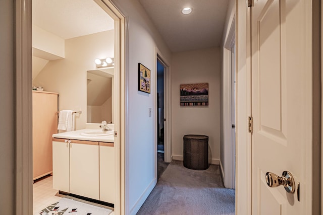 corridor featuring light colored carpet and sink