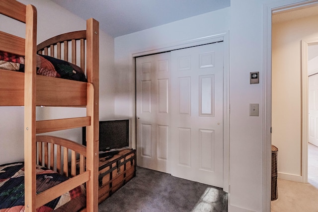 bedroom with dark colored carpet, a closet, and a crib