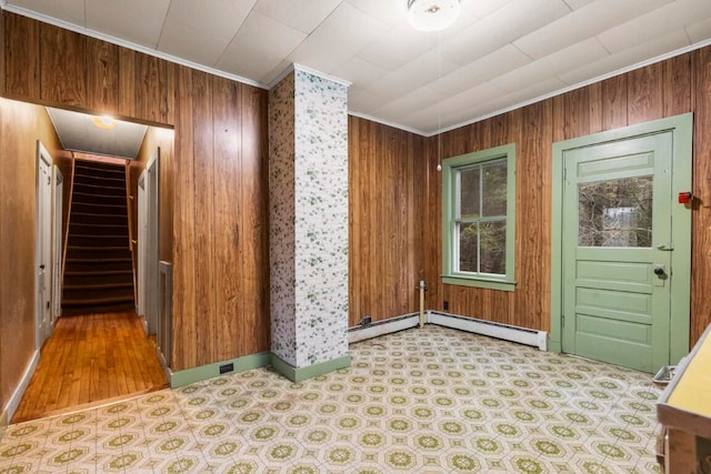 entrance foyer with a baseboard radiator, wooden walls, crown molding, and hardwood / wood-style floors