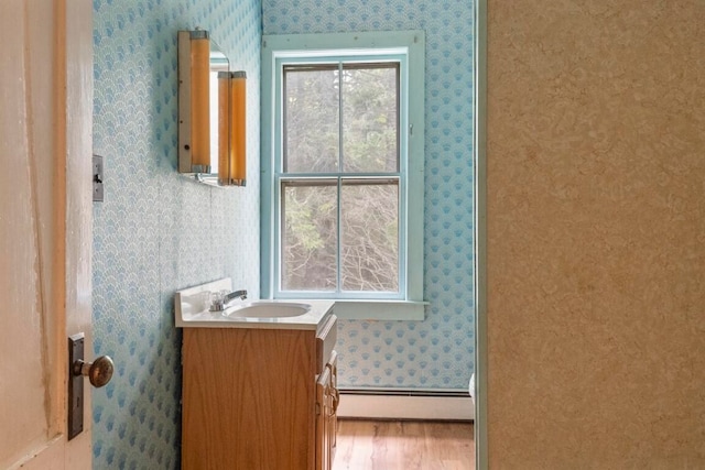 bathroom with wood-type flooring, vanity, and a baseboard radiator