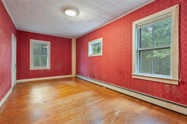 unfurnished room with ornamental molding, a baseboard radiator, and hardwood / wood-style flooring