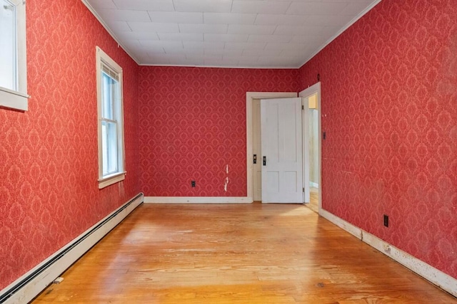 unfurnished room featuring light hardwood / wood-style floors, plenty of natural light, and a baseboard radiator