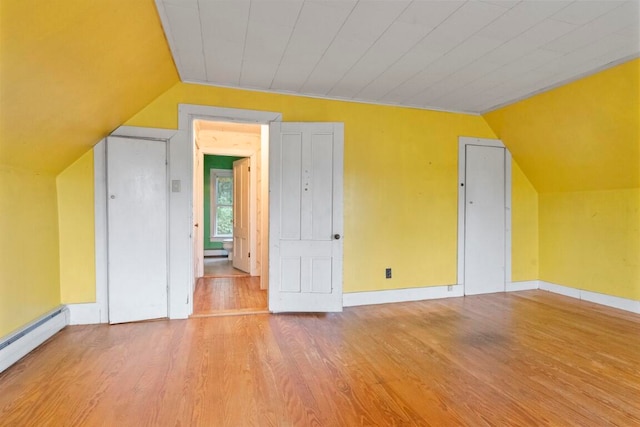 bonus room featuring a baseboard heating unit, wood-type flooring, and lofted ceiling