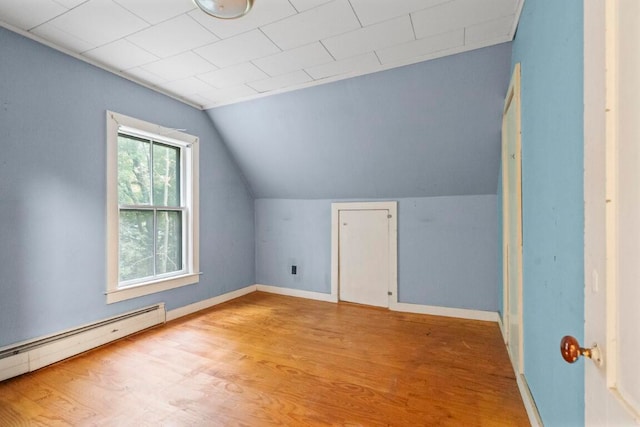 additional living space with wood-type flooring, vaulted ceiling, and a baseboard heating unit