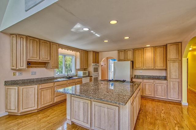 kitchen featuring white appliances, light hardwood / wood-style floors, a kitchen island, and sink