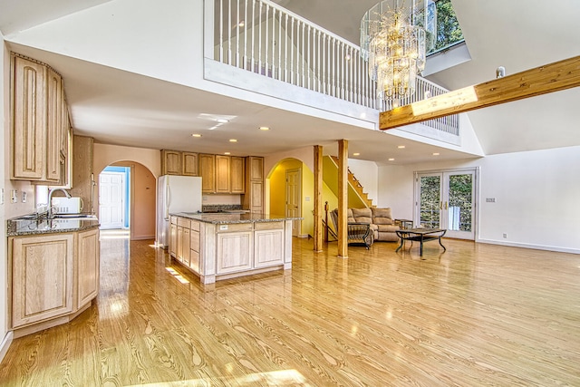 kitchen with light wood-type flooring, light brown cabinetry, white refrigerator, and high vaulted ceiling