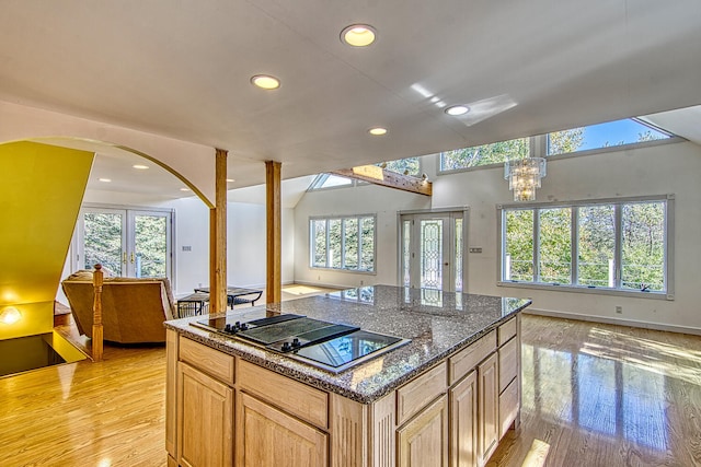 kitchen featuring black electric cooktop, light wood-type flooring, light brown cabinetry, and a wealth of natural light