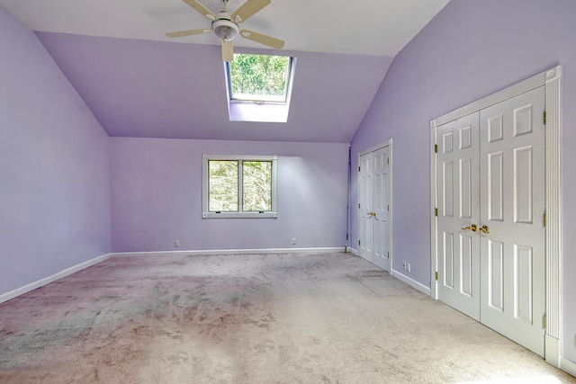 bonus room featuring lofted ceiling with skylight, ceiling fan, and light colored carpet