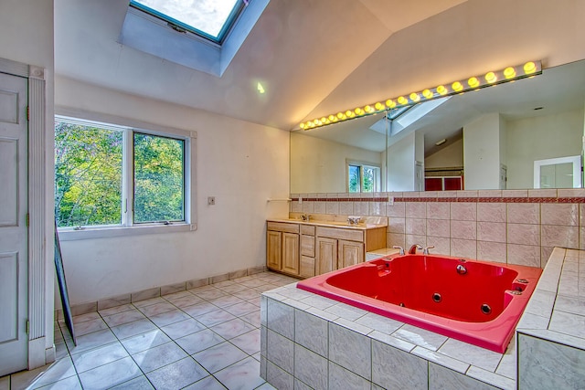 bathroom with a relaxing tiled tub, vanity, tile patterned flooring, and lofted ceiling with skylight