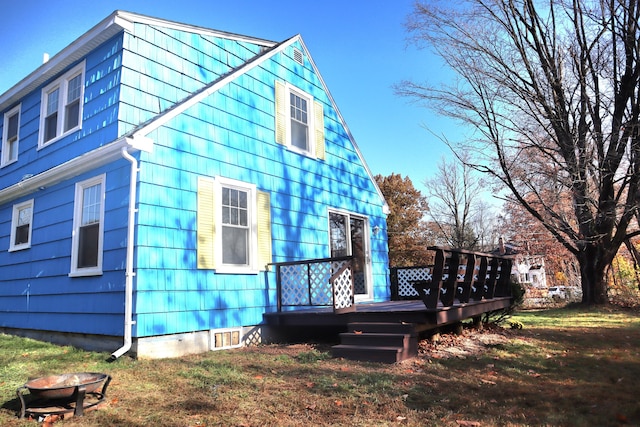 view of side of home with a deck and a lawn