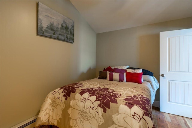 bedroom with lofted ceiling, baseboard heating, and hardwood / wood-style floors