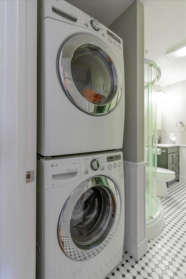 clothes washing area with stacked washer / drying machine and sink