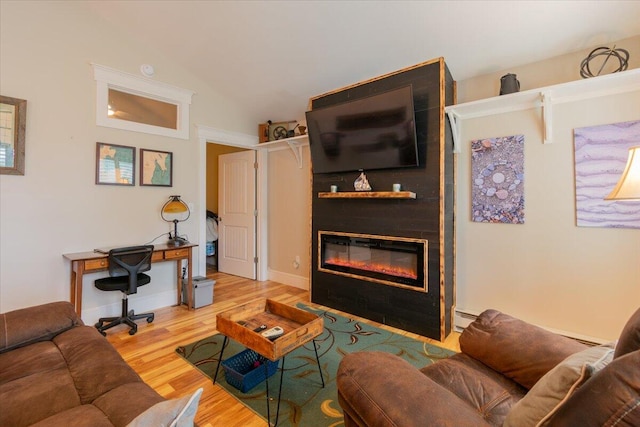 living room featuring a baseboard radiator, lofted ceiling, a fireplace, and hardwood / wood-style floors