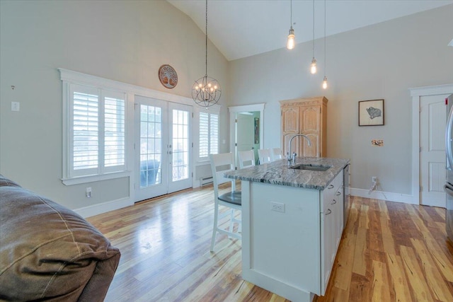 kitchen with light wood-type flooring, sink, and high vaulted ceiling