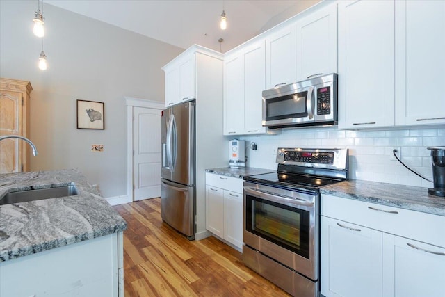 kitchen with white cabinets, lofted ceiling, appliances with stainless steel finishes, and sink