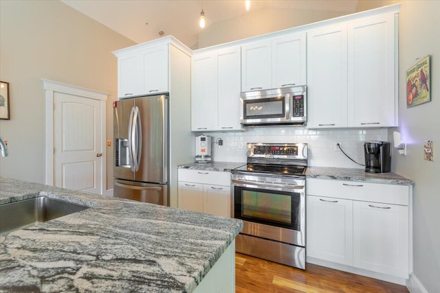 kitchen with light stone countertops, stainless steel appliances, and white cabinetry