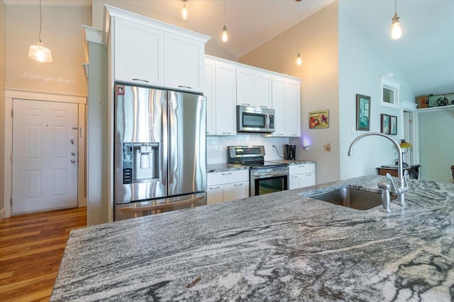 kitchen featuring pendant lighting, wood-type flooring, white cabinets, high vaulted ceiling, and appliances with stainless steel finishes