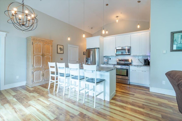 kitchen with pendant lighting, light wood-type flooring, white cabinets, high vaulted ceiling, and appliances with stainless steel finishes