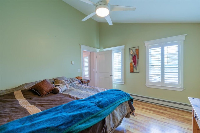 bedroom featuring light wood-type flooring, ceiling fan, a baseboard heating unit, and multiple windows