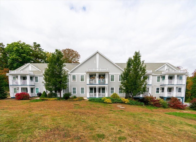 back of house with a balcony and a yard