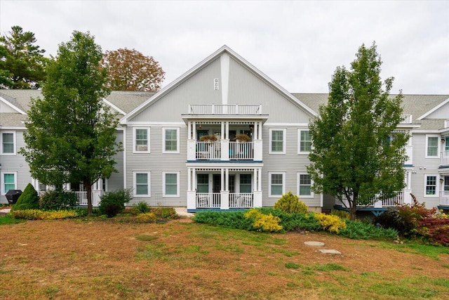 back of house featuring a balcony and a lawn