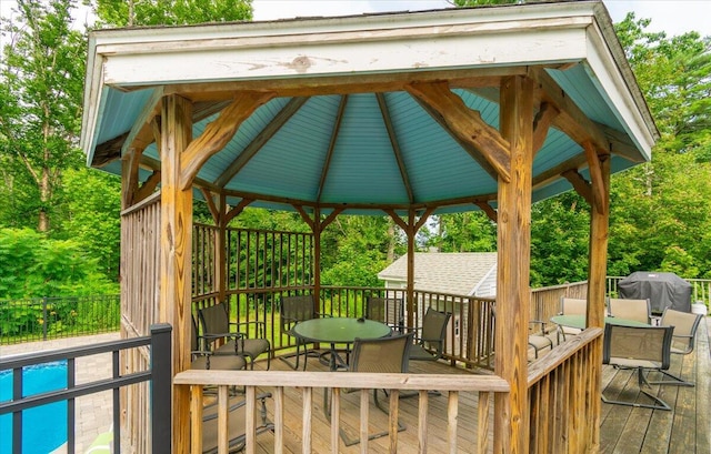 wooden terrace with a pool, grilling area, and a gazebo