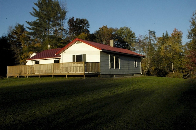 rear view of house featuring a wooden deck and a yard