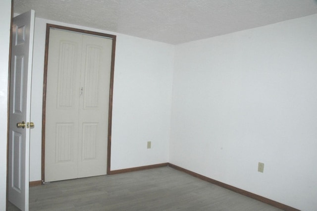 unfurnished bedroom with a closet, wood-type flooring, and a textured ceiling