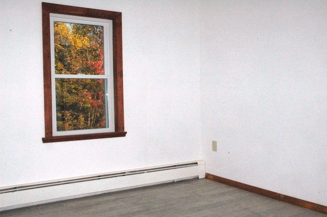 unfurnished room featuring baseboard heating and hardwood / wood-style flooring